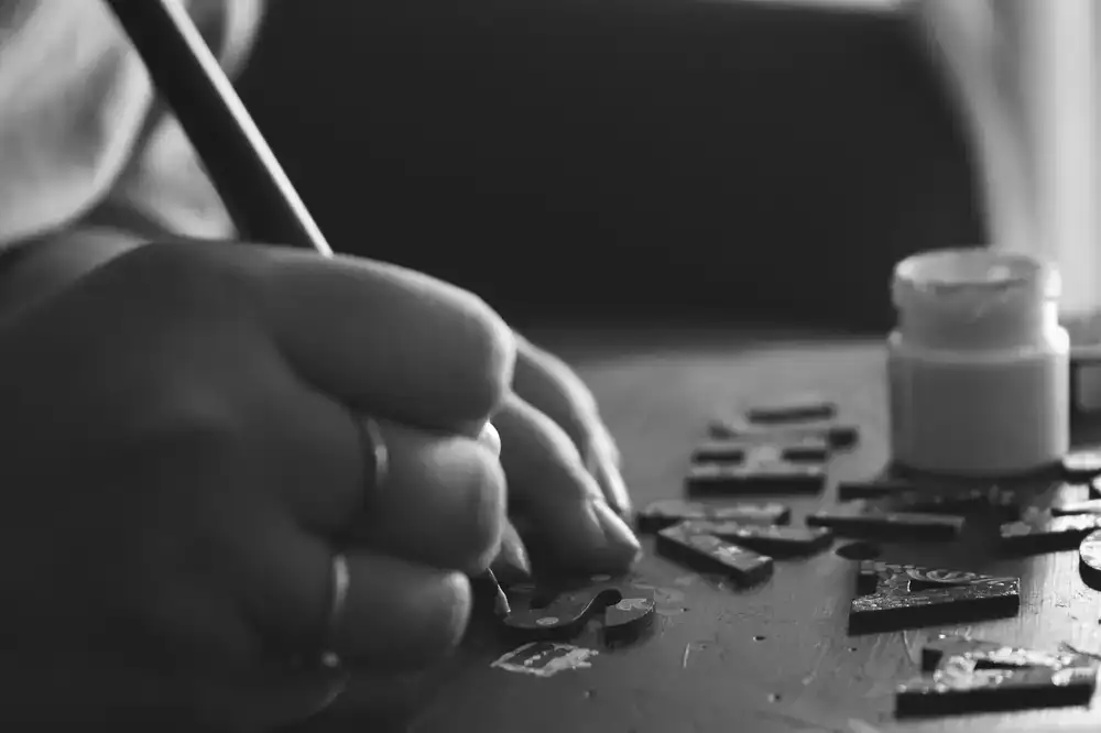 Signwriter carefully painting a letter on a wooden board