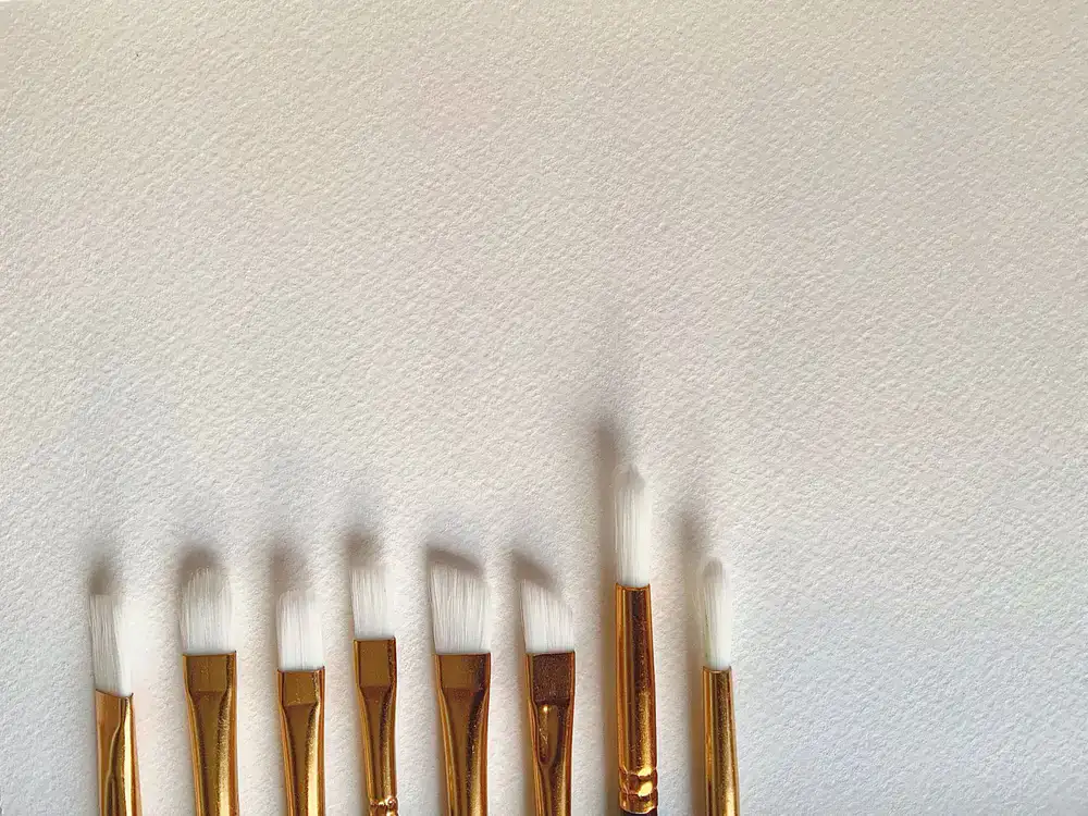 Booklets of 23ct gold leaf next to a specialized gilder's tip brush