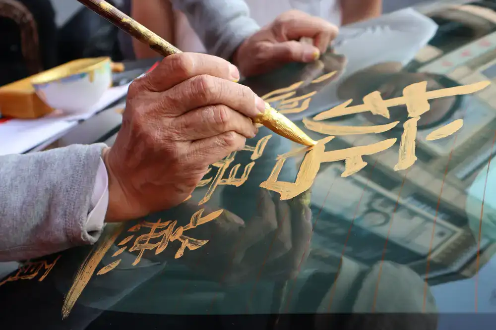 A signwriter's hand carefully painting lettering on a wooden fascia
